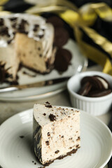 Oreo Cheesecake slice include chocolate, cream, sugar with fork and flowers served in plate isolated on napkin side view of cafe food