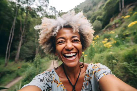 Smiling middle age black woman taking selfie while walking alone in mountains