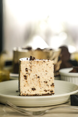 Oreo Cheesecake slice include chocolate, cream, sugar with fork and flowers served in plate isolated on napkin side view of cafe food