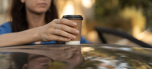 Woman putting coffee takeaway in a paper cup on top of the car roof in the morning, selective focus. Banner. - obrazy, fototapety, plakaty