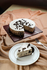 Oreo Cheesecake slice include chocolate, cream, sugar with fork and flowers served in plate isolated on napkin side view of cafe food