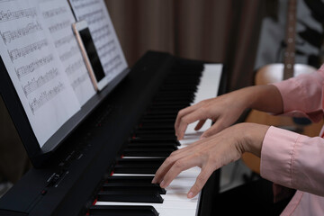 Close up woman hand playing piano at home. Relaxing time concept. Practicing music at home, Note...