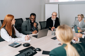 Positive African-American team leader sitting at table, sharing project ideas with mixed race...