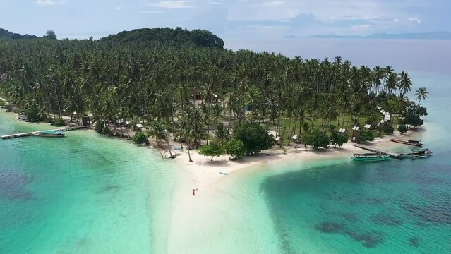 The reverse movement of the Dron camera with a beautiful view of the island in the middle of the sea. and coconut trees in the center of the island.