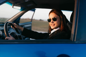 positive female driver in business clothes smiles while driving. Business driver work concept.