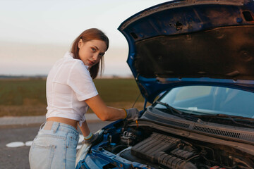 woman near a car with an open hood on the road, car breakdown.