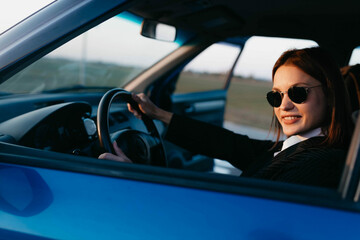 positive female driver in business clothes smiles while driving. Business driver work concept.