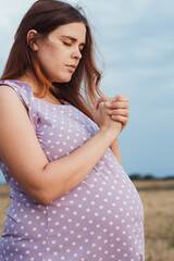 pregnant woman praying to God standing on field, gift of life