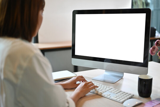 Rear view image of Businesswoman working at a blank computer monitor
