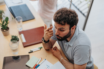 Male business person explaining something and gesturing with arm at the office.