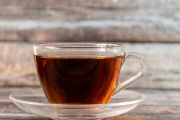 Front shot of black tea placed on wooden texture with defocused background.