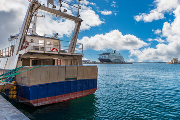 A cruise ship docking and a trawler in the foreground, in the port of Sète, France