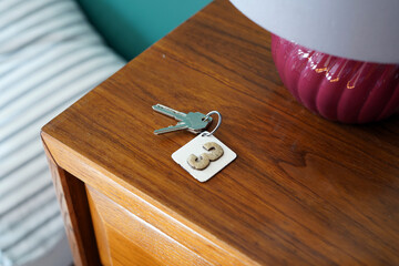 Room keys with number three placed on a wooden chest of drawers. - obrazy, fototapety, plakaty