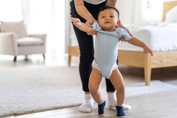 Obraz premium Portrait of enjoy happy love family asian mother playing and teaching help adorable little asian baby learning to walk.Mom help first step with cute son beginnings development at home.Love of family 