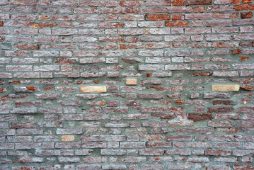 alte, verwitterte Hausmauer aus Backsteinen mit abgebröckeltem Putz