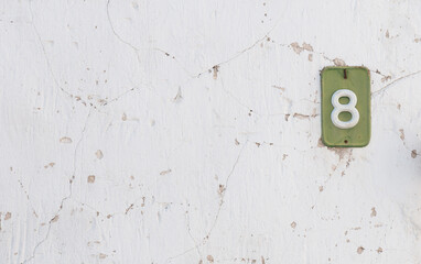Street house number 8 eight on white wall. Home residential address.