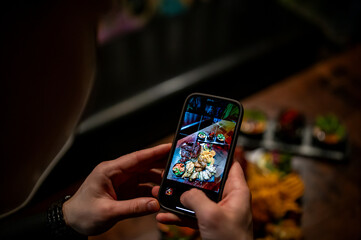 man hand with smartphone photographing food at restaurant or cafe