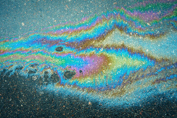 Colored oil stains close up, the color of the gasoline stain on the pavement road as a texture or background