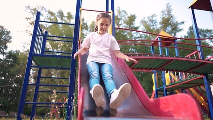 group of children slides down the slide on the playground. happy family kid dream concept. group of children on a slide outside on the playground. child playing in kindergarten outdoors lifestyle