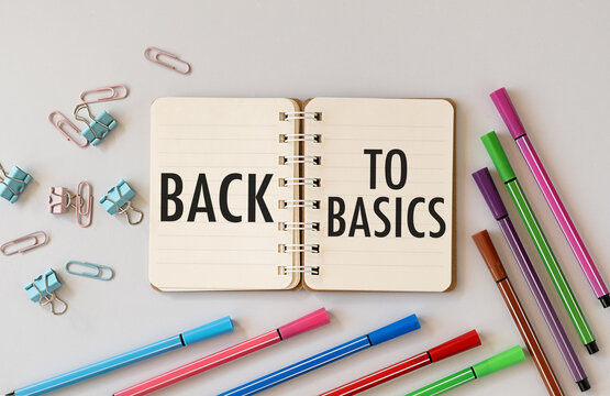 Notepad with text back to basics on table with chopsticks, colored paper clips and crumpled sheets.