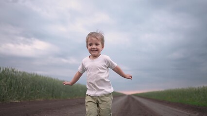 boy child running in nature in the park. happy family kid dream concept. free child son runs along a rural road next to a field in nature. free baby runs and lifestyle plays in the park