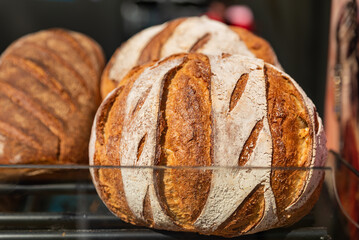 Sourdough bread with crispy crust on wooden shelf. Bakery goods , Different kinds of fresh bread as...