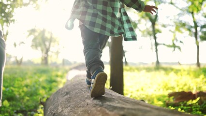 baby boy play in the forest park. close-up child feet walk on a fallen tree log. happy family kid...