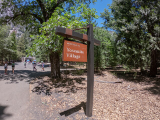 Yosemite Valley, California, USA, June 27, 2022: A wooden sign indicating the entrance to Yosemite Village in Yosemite National Park, CA.