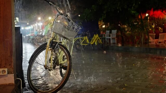 Heavy downpour in the bicycle parking at night, Retro yellow bicycle with bicycle bag, gets wet in the rain at night. yellow Bicycle stands in the rain on the street, close-up