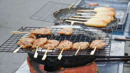 Closeup of charcoal-smoked grilled pork skewer at market stall. Tasty Thai style grilled pork. Food and nutrition concept. Roasted pork on stove - thai style