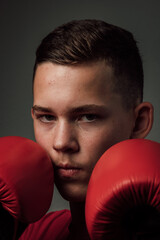 A teenage boxer athlete is training to box on dark background. Aggressive sport