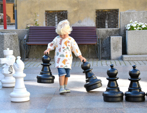 Little toddler boy playing on outdoor chess board