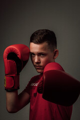A teenage boxer athlete is training to box on dark background. Aggressive sport