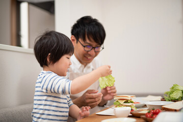 Obraz na płótnie Canvas お父さんと一緒にサンドイッチを作る子供