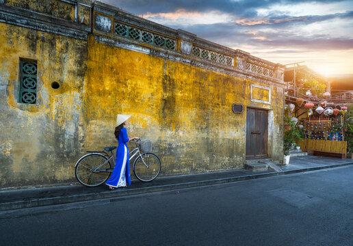 Vietnamese girls in national costumes Walk and lead an ancient bicycle. Play the old town of Hoi An, Vietnam. with a beautiful and unique architecture.