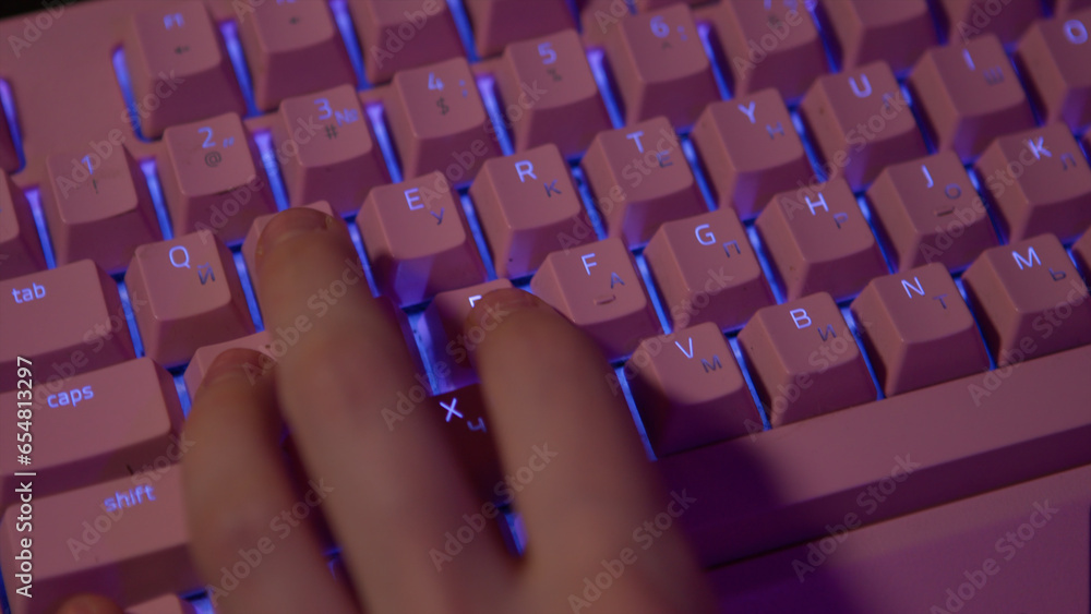 Poster close-up of fingers pressing on keyboard during game. stock footage. pink glowing keyboard for compu