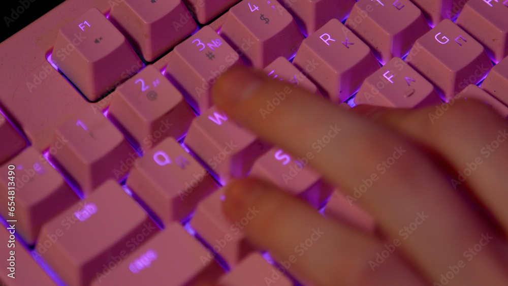 Poster close-up of fingers pressing on keyboard during game. stock footage. pink glowing keyboard for compu