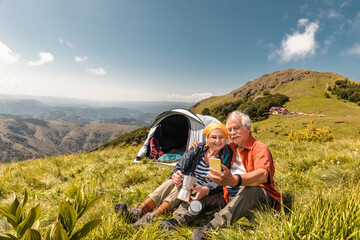 Senior Caucasian couple using a smartphone while camping and hiking in the mountains