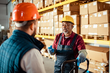 Mature African American man giving advice to a coworker in a warehouse