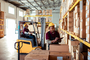 Mature African American worker doing inventory on boxes in a warehouse