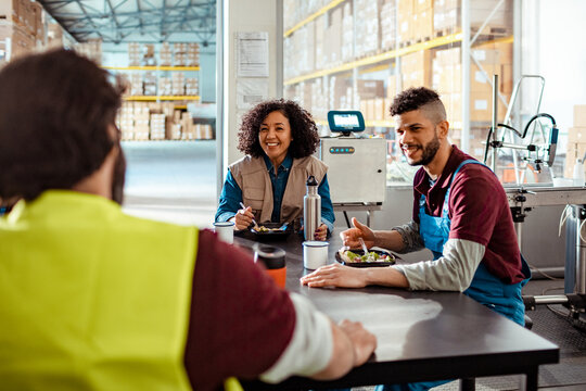 Group of young and diverse workers having a lunch break in a warehouse , African American