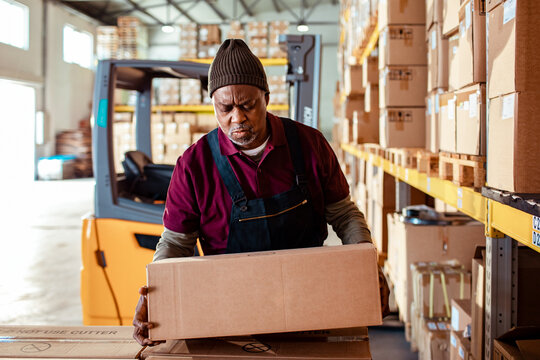 Mature African American worker moving boxes in a warehouse