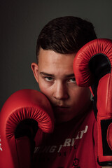 A teenage boxer athlete is training to box on dark background. Aggressive sport