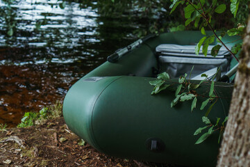 Modern inflatable boat for floating and relaxing on water parked on shore in rural site, standing near lake in evening.