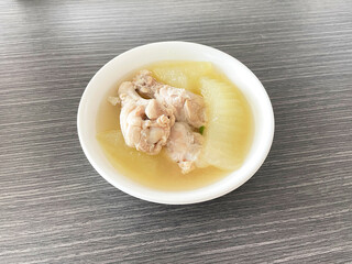 Clear soup with chicken and winter melon white bowl on wood