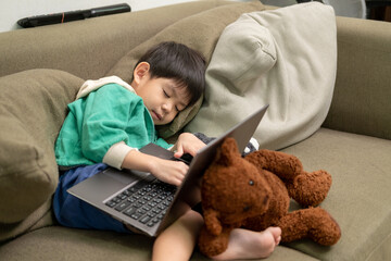 Asian boy sleeping while studying online on laptop