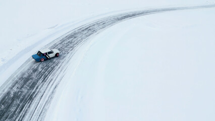 Aerial view of a race car moving fast through the snow desert. Clip. Concept of active lifestyle and sport.