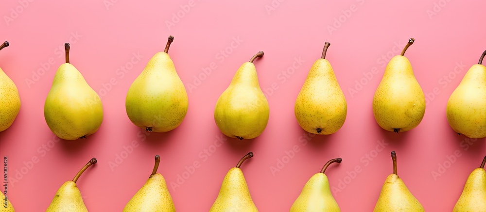 Poster top view of fresh pears arranged on a pink background with a vibrant fruit pattern with copyspace fo