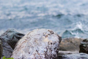 Close-up of a stone by the sea. The rock in the foreground and the sea in the background.
