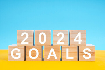 The Wooden cubes 2024 GOALS on yellow and blue background. Planning and goals concepts on 2024 year.
